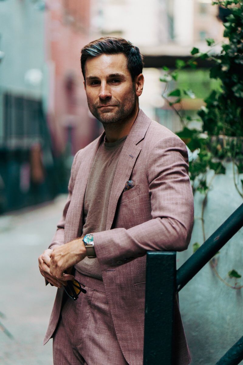Shane in a dusty rose blend suit and taupe crewneck tee, styled with a pocket square and watch