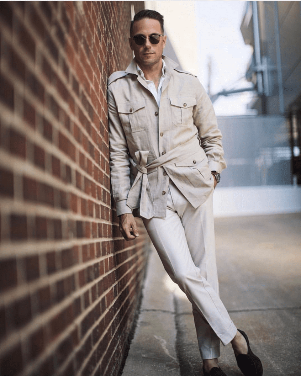 (product) Stone Solid Linen Safari Shirt Jacket, styled with white trousers and sunglasses against a brick wall